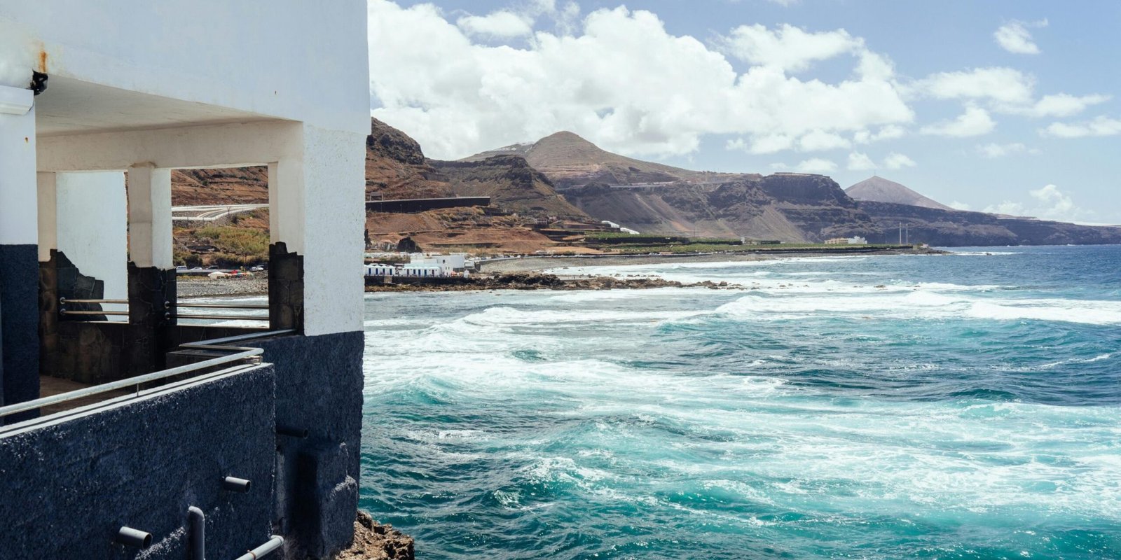 Breathtaking coastal view of Gran Canaria with waves hitting the shore under a sunny sky.